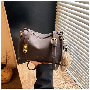 Détail de sac en cuir marron vintage avec texture litchi et pendentif ours mignon