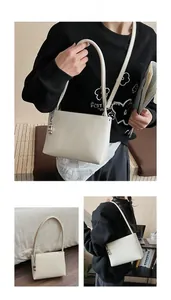 Detail view of cream leather bucket bag with silver chain strap and metal charm