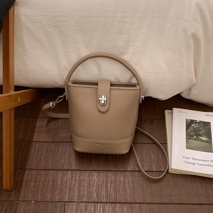 Close-up of khaki bucket bag showing litchi texture leather and silver twist-lock closure
