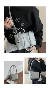 Detail view of light green underarm bag with silver bean pendant and matte finish