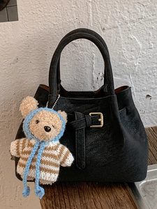 Vintage black bucket bag with lychee texture, gold buckle, and cute bear charm pendant