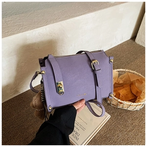 Détail du sac violet en similicuir avec garnitures dorées et pompon marron décoratif