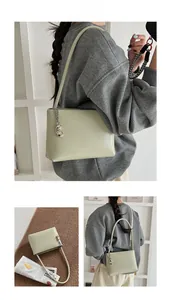 Detail view of light olive leather bucket bag with silver chain and metal charm