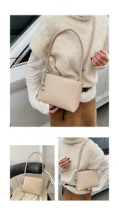 Detail view of a beige minimalist shoulder bag featuring an elegant silver bear chain pendant