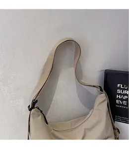 Detail view of the smooth beige nylon crossbody bag featuring a wide adjustable shoulder strap