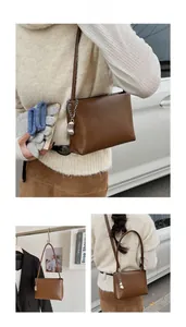 Detail view of brown soft leather bucket bag with silver chain and metal charm detail