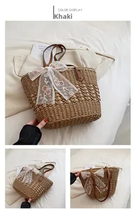 Detail view of khaki straw tote bag with white lace bow and floral embroidery decoration