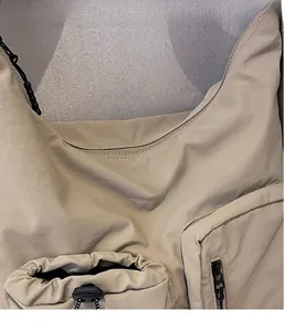 Detail of functional drawstring pocket and durable nylon fabric on beige crossbody bag