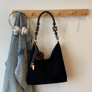 Détail du cabas vintage en daim avec bandoulière en perles de bois et pompon doux