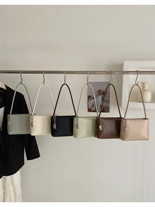 Row of colorful minimalist leather underarm bags hanging on a rack with metal charms
