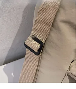 Detail view of the black adjustable buckle and woven strap on the khaki crossbody bag