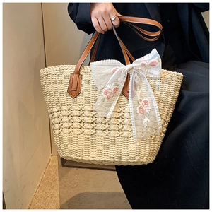 Detail of straw tote bag with white lace bow and delicate pink floral embroidery