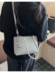 Detail of light gray PU leather shoulder bag with silver chain and bean shaped charm