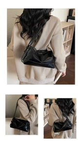 Detail of black glossy faux leather underarm bag with adjustable strap and metal eyelets