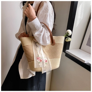 Detail of hand-woven straw tote with white lace and pink floral embroidery details