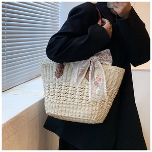 Detail of hand-woven straw tote bag with lace bow and floral embroidery work