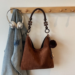 Détail du sac cabas en daim avec perles en bois décoratives et charmant pompon en peluche
