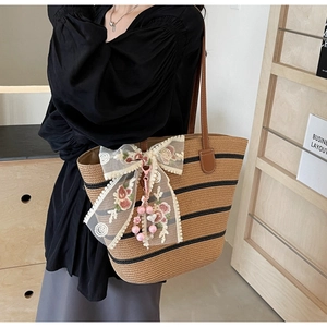 Detail der Strohtasche mit schwarzen Streifen, Spitzenschleife und Blumenstickerei-Details