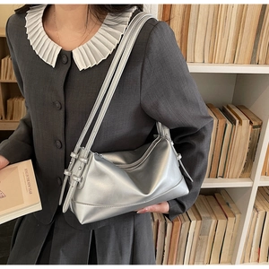 Detail of silver metallic underarm bag with double thin straps worn by a model in a library