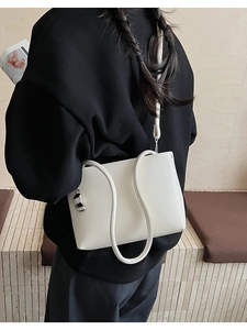Detailed macro view of the cream white leather shoulder bag with a silver fashion pendant