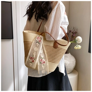 Detail of gradient woven straw tote featuring lace embroidery and brown leather straps