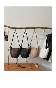 Minimalist bucket bags in four colors hanging on a wooden branch with leather texture details