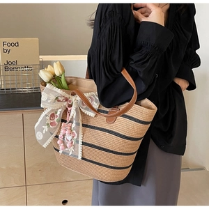 Detail der gewebten Strohtasche mit schwarzen Streifen und Spitzen-Schleifen-Anhänger