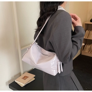 Detail view of light purple patent leather shoulder bag with zipper and adjustable strap