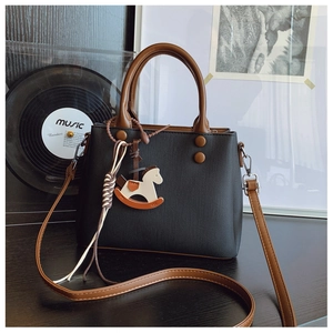Detail of black mini square bag with brown rivets and rocking horse pendant charm