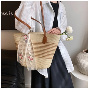 Detailed close-up of straw tote bag featuring brown leather handles and rose lace scarf