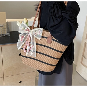 Detail der Strohtasche mit schwarzen Streifen, Ledergriffen und Spitzenbogendekor