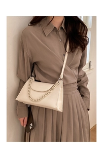 Detailed macro view of the white lychee leather texture and thick chain on the shoulder bag