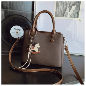 Detail view of brown cross-grain handbag with unique wooden horse charm and handles