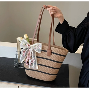 Detail der Strohtasche mit floraler Spitzen-Schleife und hochwertigen Ledergriffen