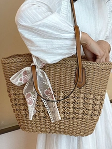 Handwoven straw tote bag with white lace floral scarf and brown leather shoulder straps