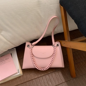 Detailed macro view of the light pink lychee texture leather and gold logo on the handbag