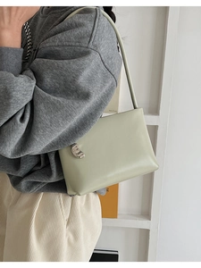 Side view of model wearing a light pea green leather shoulder bag with silver buckle