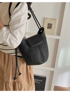 Detail view of black lychee grain leather tote bag with knot shoulder strap on minimalist shelf
