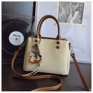 Detailed view of vintage canvas and leather handbag with horse charm and brown strap