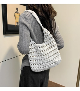 Detail of white handmade crochet tote bag with openwork weave on female model shoulder