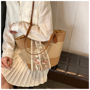 Detailed side view of a woven straw tote with floral lace embroidery and leather straps