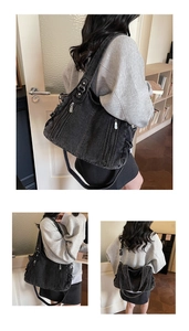 Detail of black denim shoulder bag featuring functional zip pockets and adjustable strap