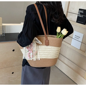 Detailansicht der gewebten Strohtasche mit braunem Lederriemen und Spitzen-Schleife