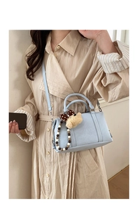 Detail of light blue Boston bag with plush bear charm and beaded handle on a model