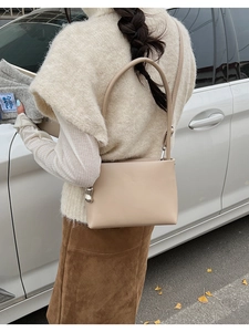 Detail view of stylish cream beige underarm bag on shoulder showing modern casual look