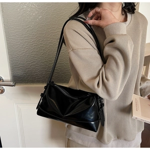 Detail of minimalist black shiny leather underarm bag with double slim shoulder straps