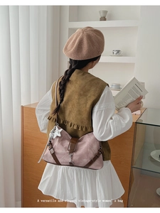 Close-up of pink shoulder bag with brown leather trim and a silver star pendant detail