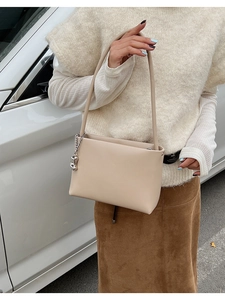 Macro shot of stylish cream shoulder bag featuring silver chain detail and smooth leather texture