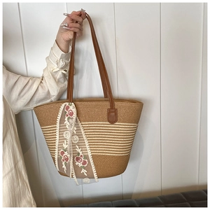 Detail view of woven straw tote bag with white stripes and elegant floral lace scarf