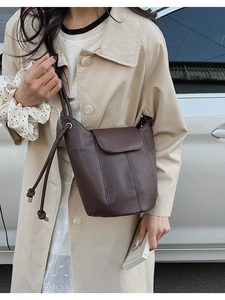 Close-up of deep brown lychee texture leather bucket bag with elegant knot strap detail